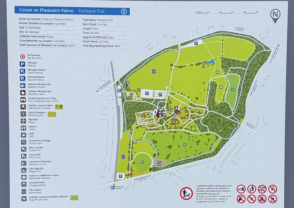 Visitor map of Malahide Castle and Gardens showing walking trails, castle, walled garden, visitor centre, and park facilities in both English and Irish.