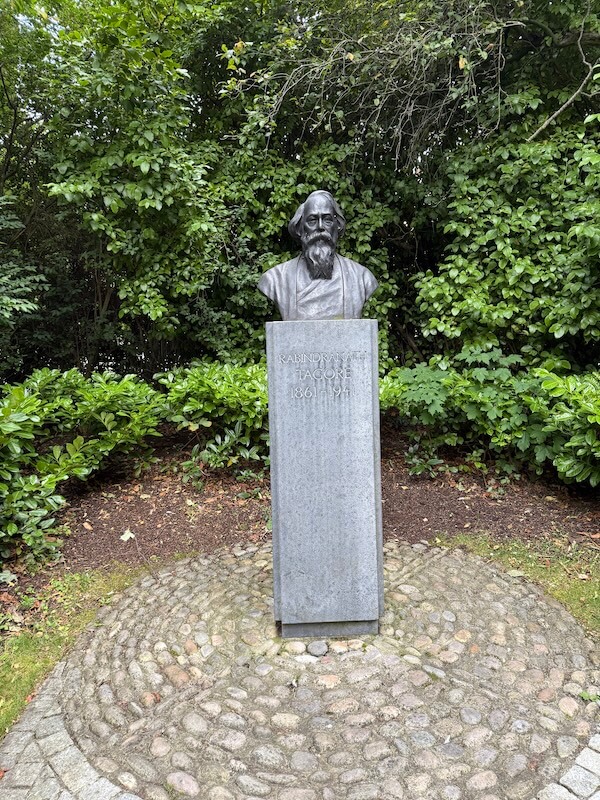 Bust of Indian poet Rabindranath Tagore mounted on a tall stone plinth in a quiet, tree-lined area of St. Stephen’s Green. The plinth is inscribed with his name and dates: 1861–1941, set on a circular cobblestone base.